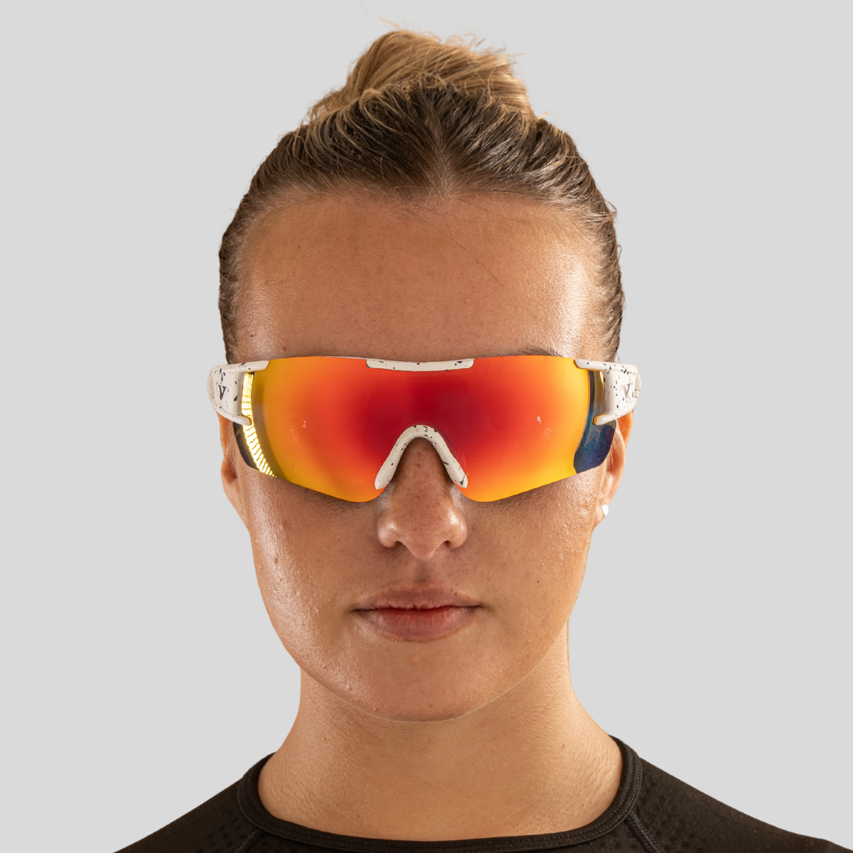 Woman models face wearing red/orange velocity sports sunglasses
